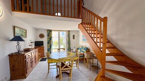 A spacious kitchen with a dining area, wooden staircase, and a view of the outdoors. - Charming house near sea - 4 guests (Saint-Jean-de-Monts)
