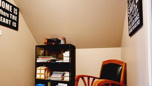 A room with a bookshelf, a wooden chair, and two motivational signs on the walls.