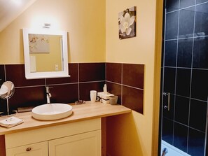 Une salle de bain avec un lavabo rond, un miroir, une serviette et des toilettes.