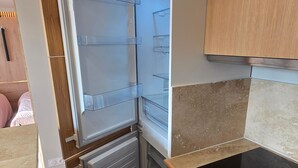 A kitchen with a built-in refrigerator, a countertop, and wooden cabinets. - Apartment at the foot of the slopes - 6 guests (Besse-et-Saint-Anastaise-Super Besse)