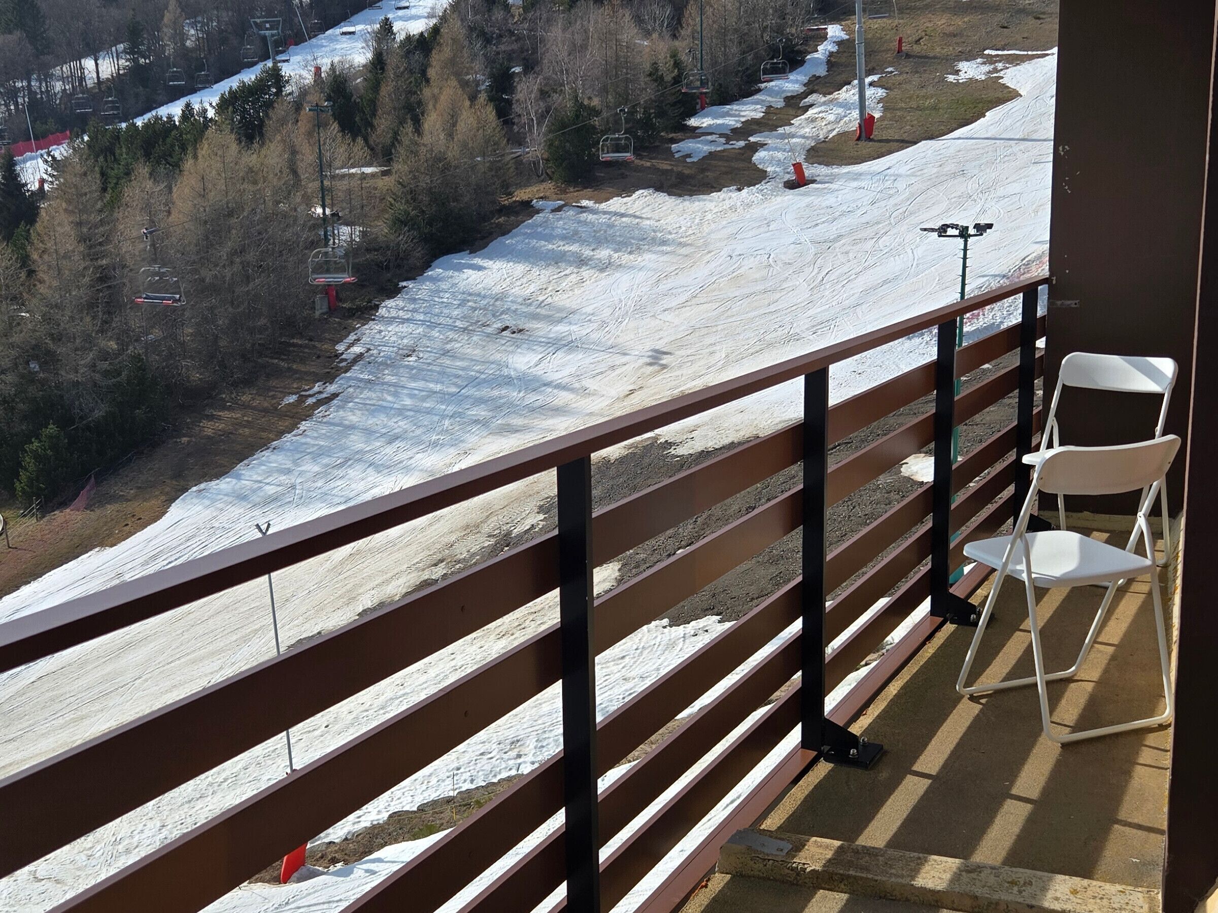 Een balkon met uitzicht op een piste, een stoel en een leuning.