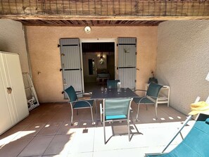 Eine Terrasse im Freien mit Tisch und Stühlen, einer Tür und Blick ins Haus.