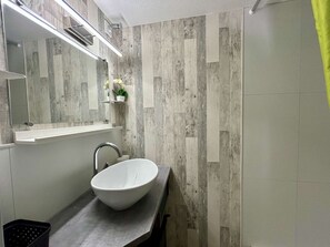 Ein Badezimmer mit einem weißen Waschbecken, einem Spiegel und einer Duschkabine.