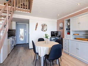 Eine moderne Küche mit Essbereich, einer Holztreppe und einem Fernseher.