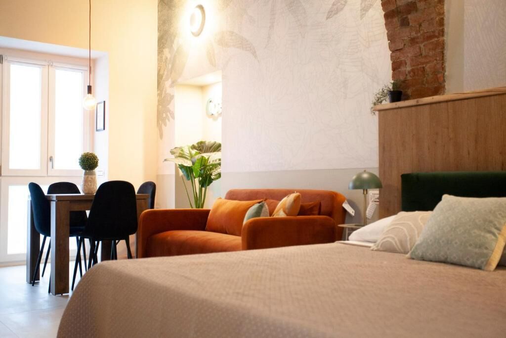 A room with a bed, a desk, chairs, and a large window.
