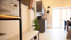 A modern kitchen with a built-in stove, a dining area with a table and chairs, and a bench with a potted plant. - Switch holiday 314 (La Spezia)