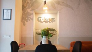 A dining area with a wooden table, black chairs, a red chair, a wall-mounted sign reading 'CUISINE,' and a decorative plant. - Switch holiday 314 (La Spezia)