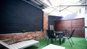 A patio area with a table and chairs, a white bench, and a brick wall. - Switch holiday 314 (La Spezia)