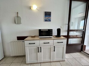 A kitchenette with a built-in oven, a coffee maker, and a poster on the wall. - Studio cabin, canal view - 4 guests (Cap d'Agde)