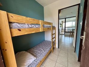 A bunk bed in a room with teal walls, a tiled floor, and a view into another room with a dining area. - Studio cabin, canal view - 4 guests (Cap d'Agde)