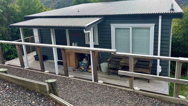 A cabin with a porch, a sign reading 'The Cabin,' and a view of a hill.