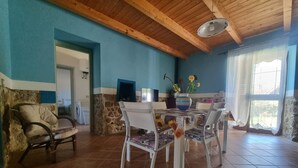 A dining area with a wooden ceiling, a stone wall, and a tiled floor. - Casa Lara: Holiday Home with Private Garden and Wi-Fi (Cannigonis)