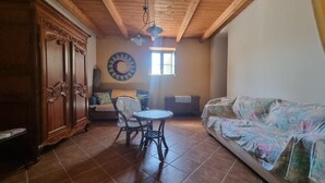 A room with a wooden ceiling, a round table with chairs, a sofa, a cabinet, and a wall clock. - Casa Lara: Holiday Home with Private Garden and Wi-Fi (Cannigonis)
