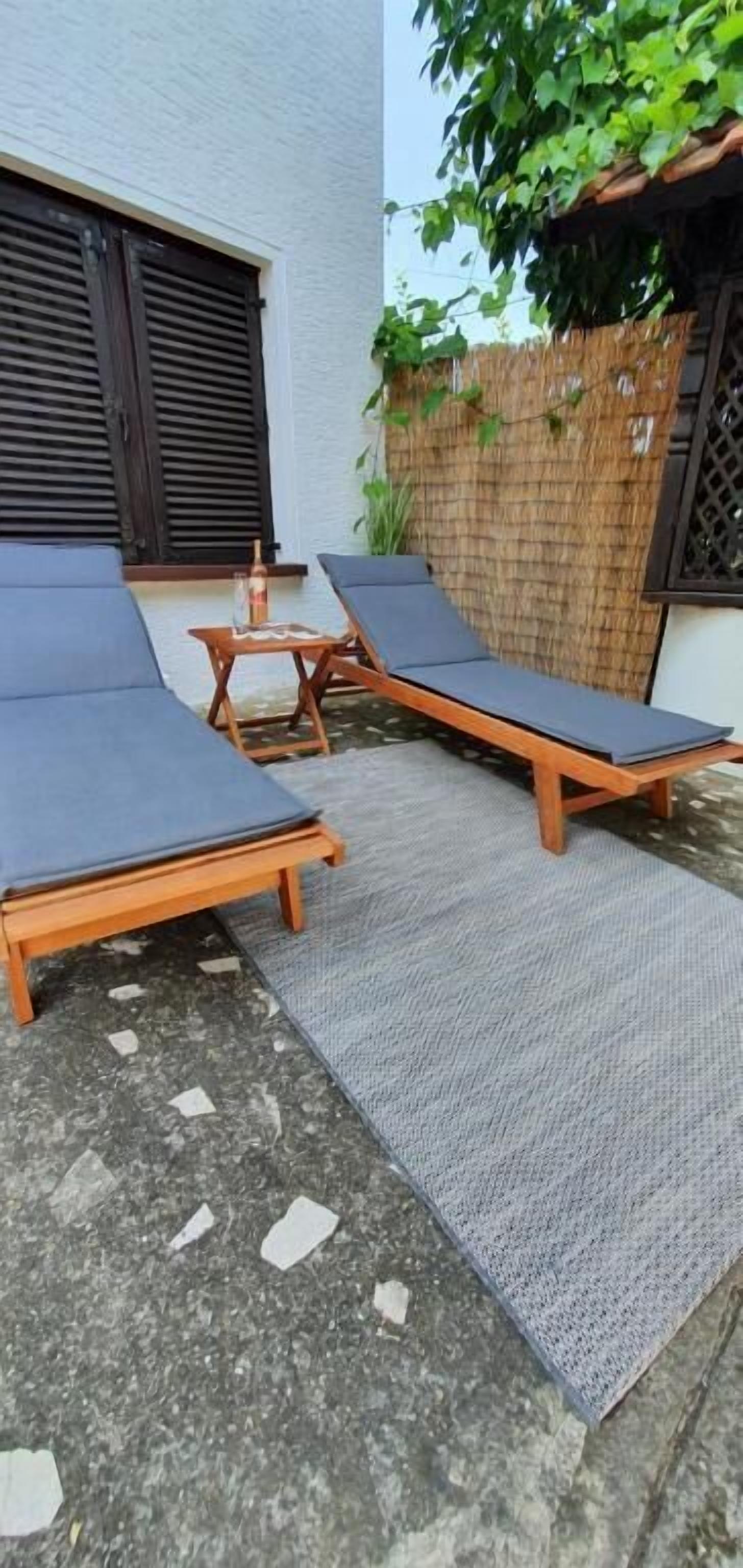Un patio con dos sillones, una mesita y una botella.