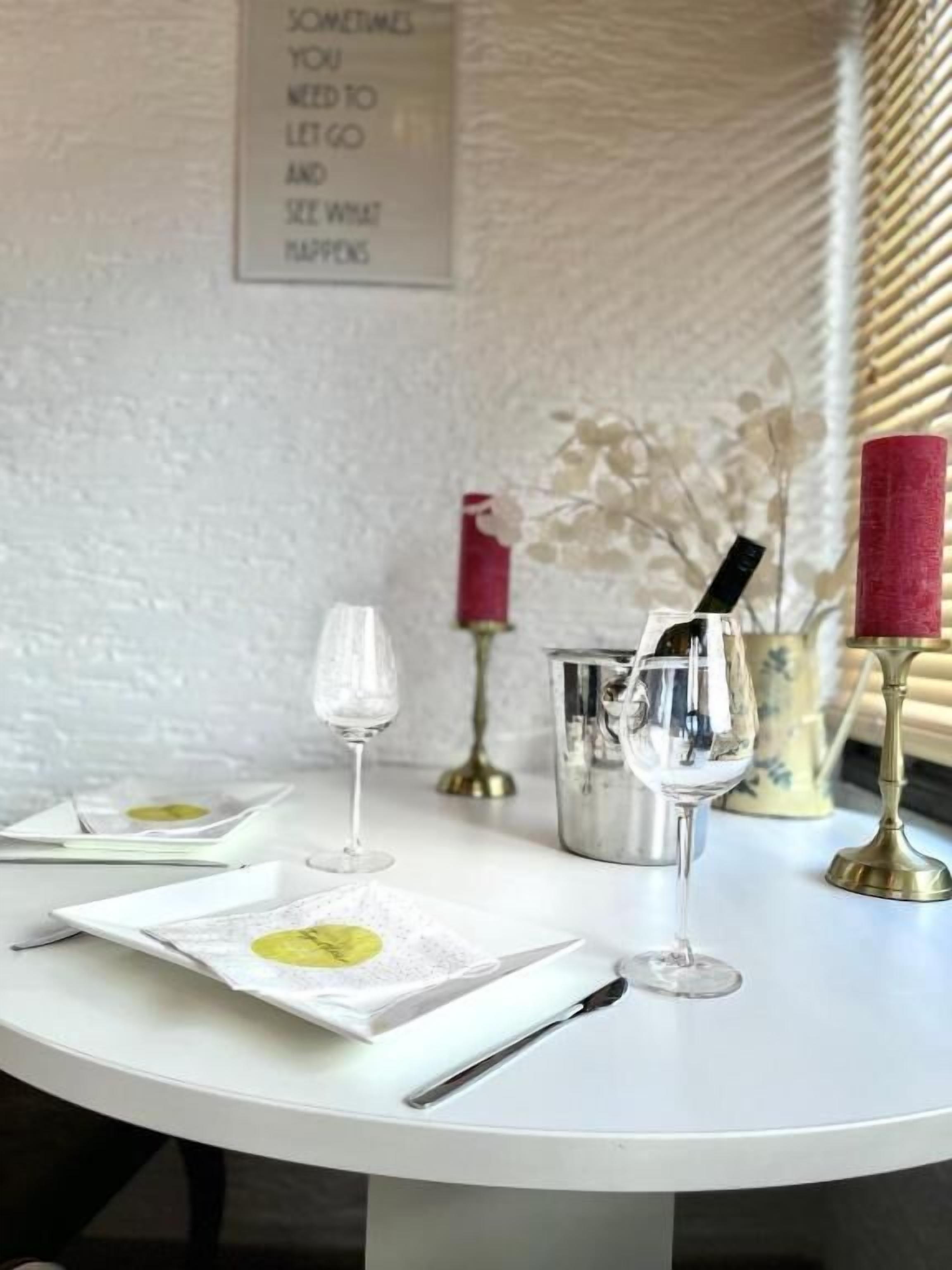 Una mesa dispuesta con platos, copas de vino y un candelabro.