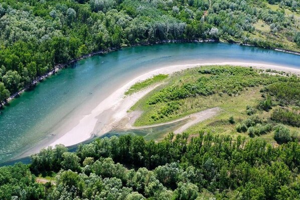 Vista aérea de una zona costera con una línea de costa curva, abundante vegetación y un cuerpo de agua transparente.