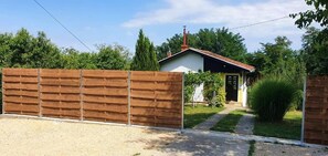Een omheind perceel met een grindpad dat naar een huis leidt, met een rood dak en een kleine tuin.