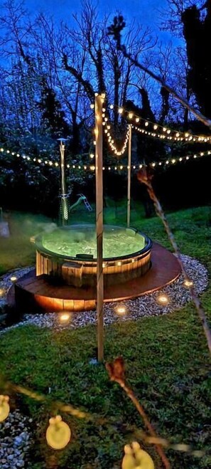 Un espacio exterior circular con una fuente central, rodeado por un sendero pavimentado e iluminado con luces colgantes.