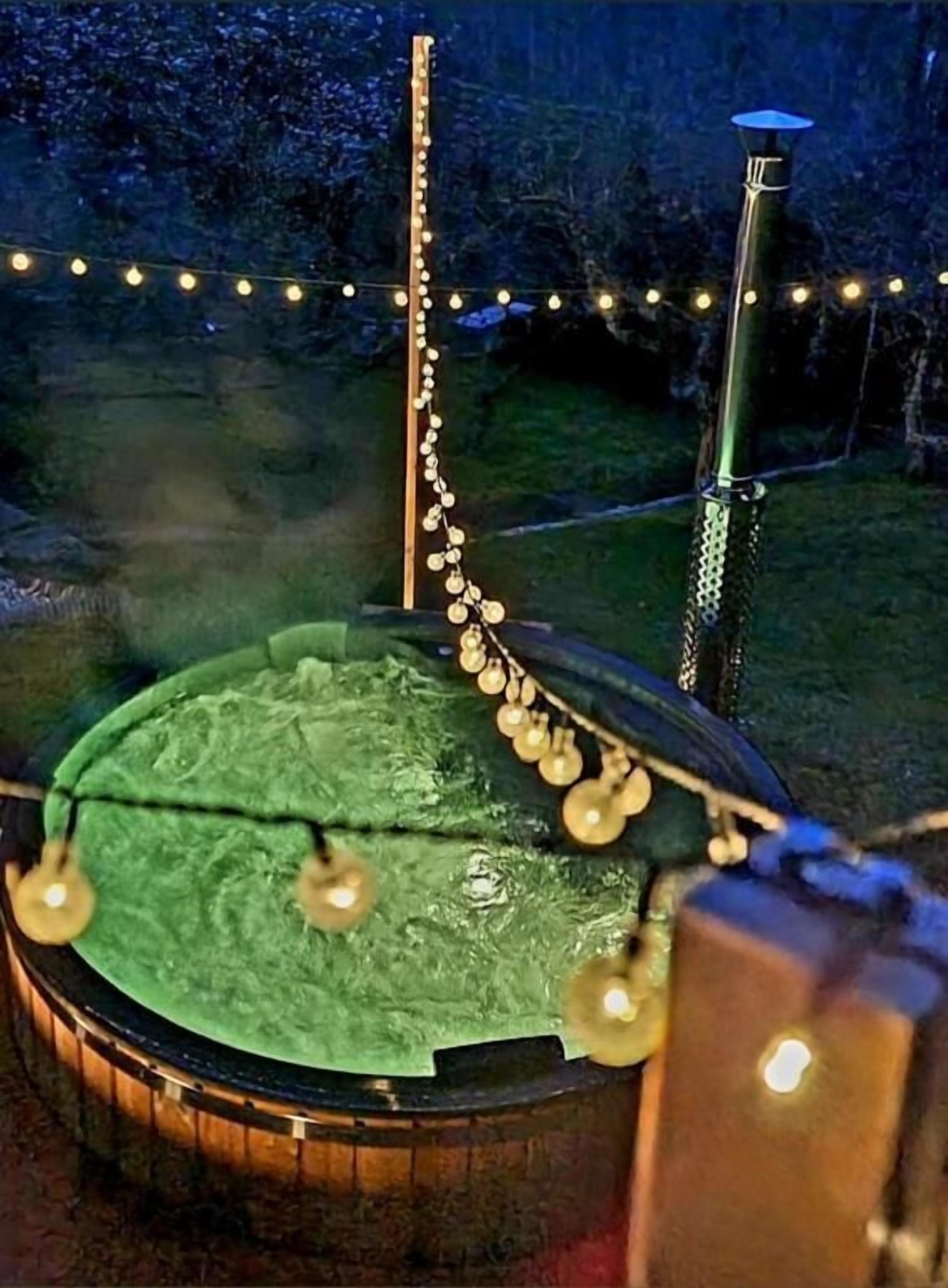 Un'area cucina all'aperto circolare con una griglia, un palo verticale e luci a stringa.