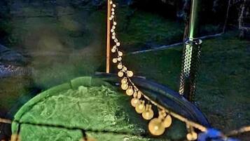 Un'area cucina all'aperto circolare con una griglia, un palo verticale e luci a stringa.