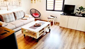 Una sala de estar acogedora con un sofá, una mesa de centro, un televisor y un aparador.