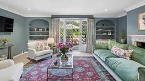 Una sala de estar con sofá, sillón, mesa de centro y estanterías.