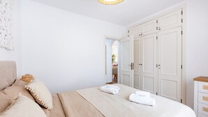 Una camera da letto con un letto, cuscini, un armadio e un comodino.