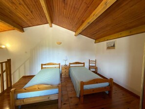 A room with two wooden beds, a wooden chair, a small table, and a ceiling light. - Spacious, cozy studio with a loft in the Verdon! (Castellane)