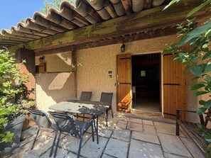 A patio with a table and chairs, a wooden door, and a stone wall. - Spacious Studio in Castellane (Castellane)