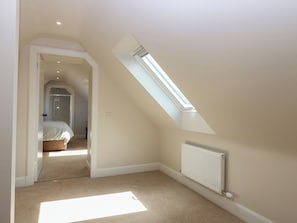 A bedroom with a sloped ceiling, a skylight, a radiator, and a carpeted floor.