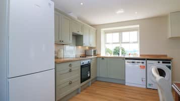 A kitchen with a refrigerator, oven, microwave, sink, and washing machine.