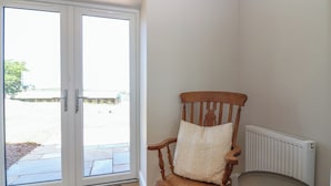 A room with a wooden chair, a small table, a radiator, and a sliding glass door leading outside.
