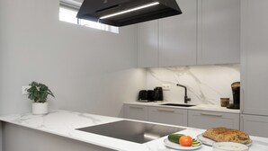 Una cocina moderna con encimera de mármol blanco, estufa integrada, un lavamanos y una planta en maceta.