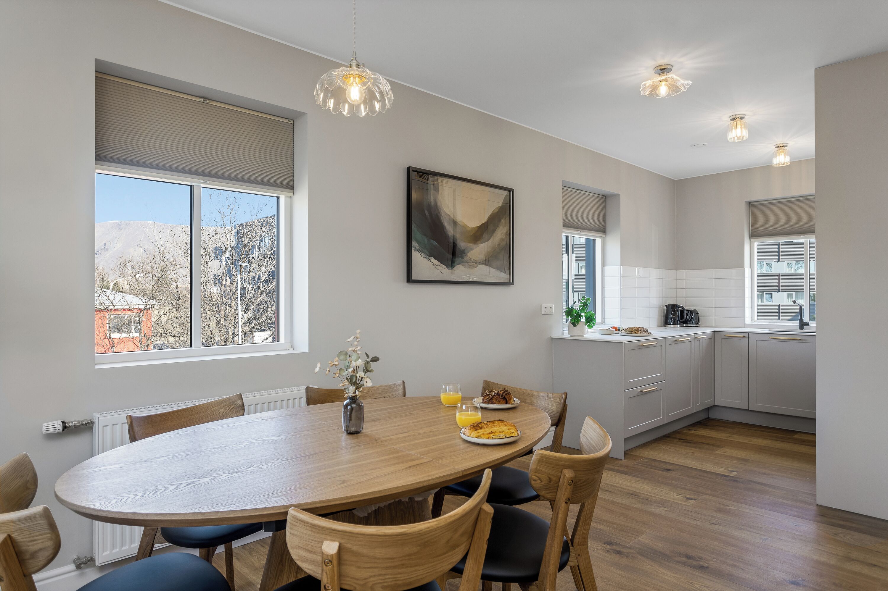 A modern kitchen with a dining area, large windows, and a view of the outdoors.