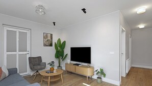 Una sala de estar moderna con un sofá gris, una mesa de centro de madera, un sillón gris, una planta verde grande, un televisor de pantalla plana y un mueble de madera.