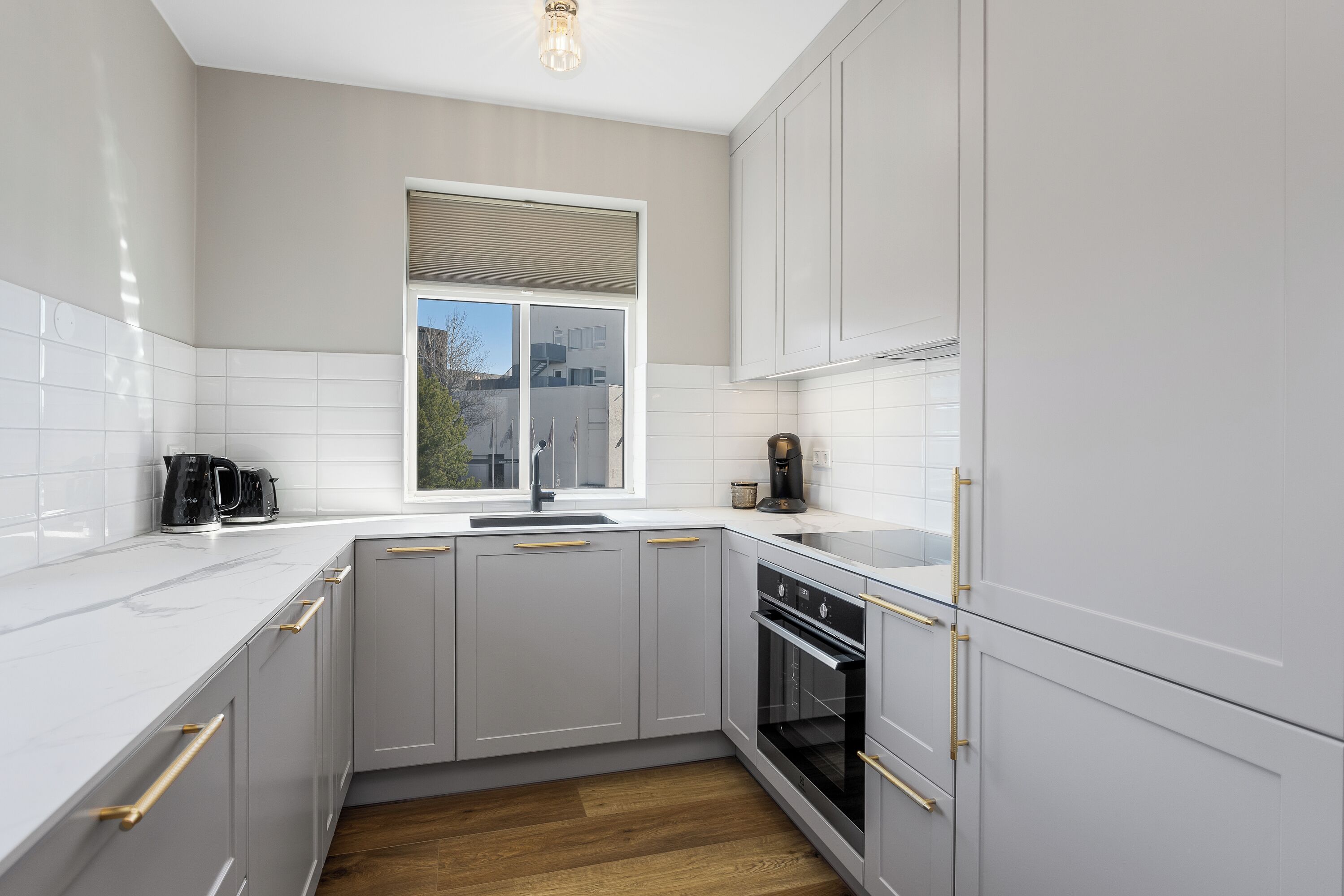 A modern kitchen with white cabinets, a built-in oven, and a window.