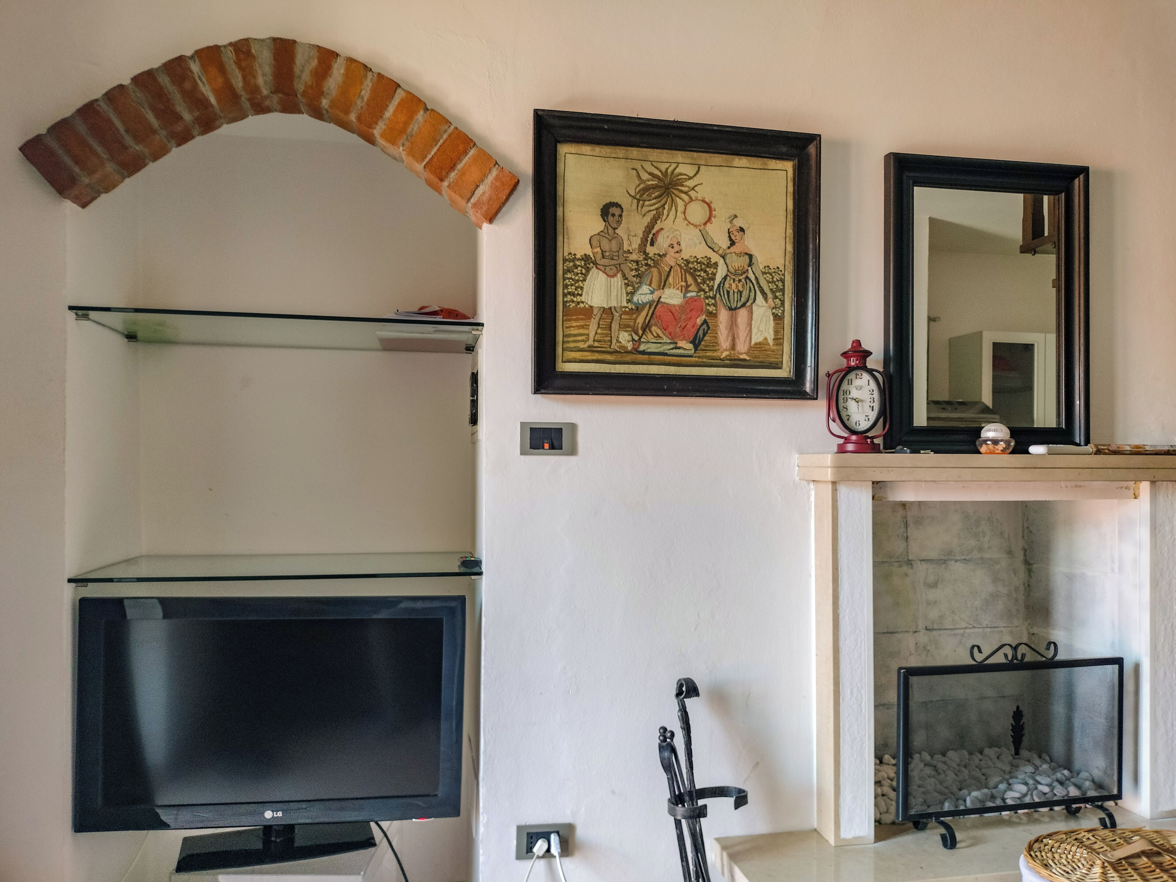 Ein Wohnzimmer mit Fernseher, Kamin, gerahmten Kunstwerken und einer Uhr.