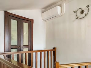 A staircase with wooden railings, a door with glass panels, and an air conditioning unit mounted on the wall. - EnDi (Asti)