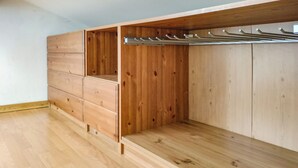 Een kamer met houten vloer, een ingebouwde kledingkast met meerdere lades en een metalen kapstok.