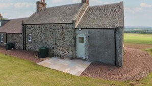 A stone building with a sloped roof, a door, and a small window. - Keepers Cottage (Haddington)