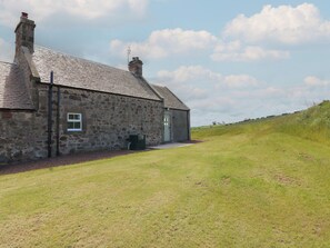 A stone building with a sloped roof, a small window, and a door.