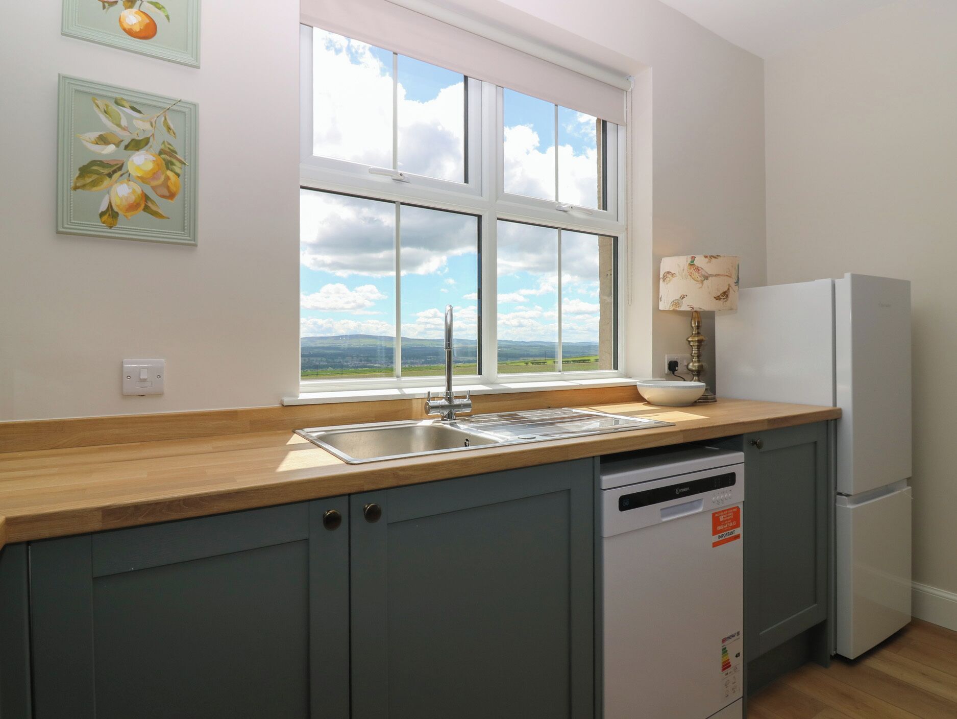 A kitchen with a window, a sink, a dishwasher, and a refrigerator.