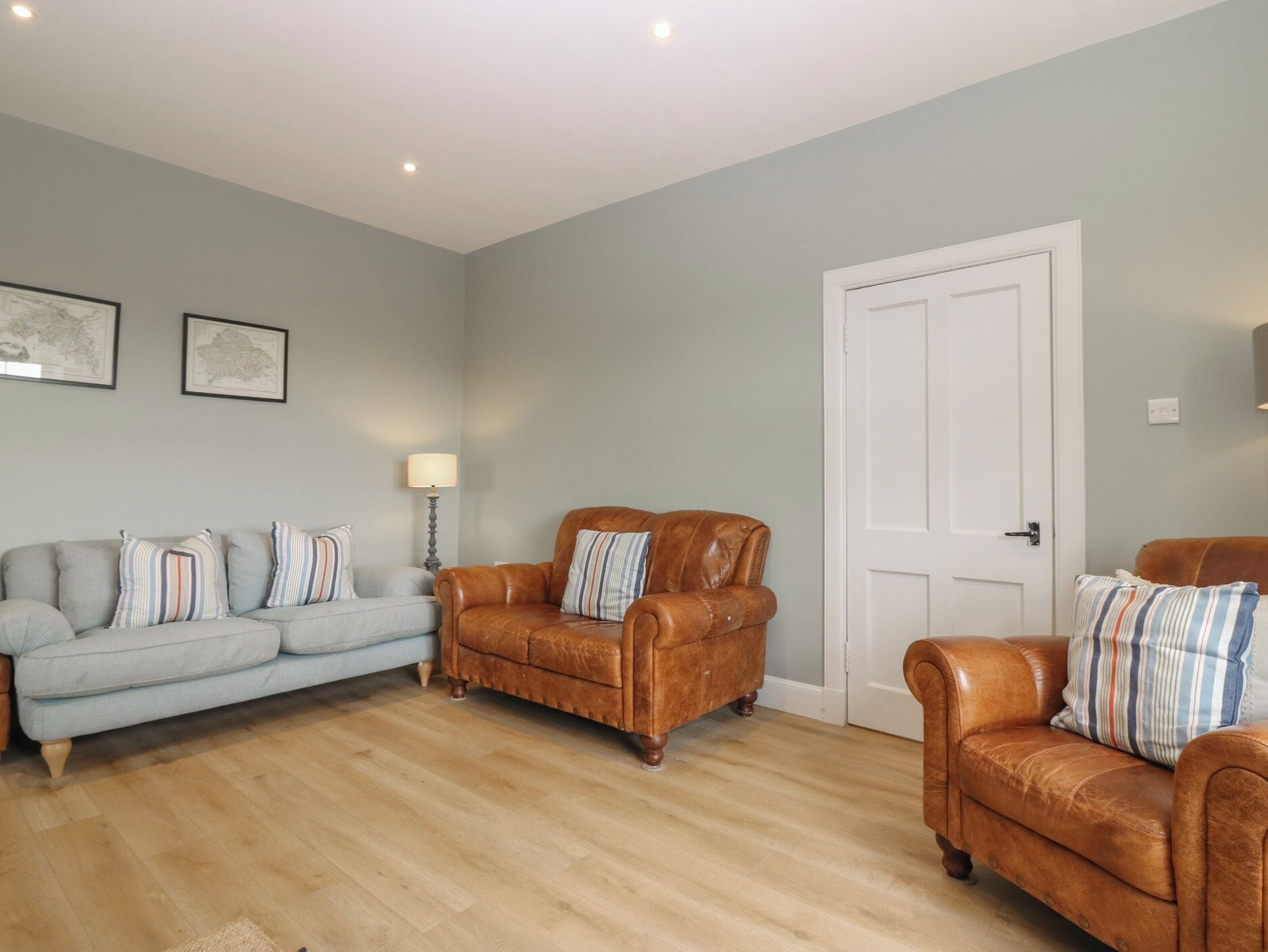 A living room with a light blue sofa, a brown leather armchair, and a white door.
