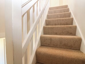 Una escalera con peldaños alfombrados y barandillas blancas.