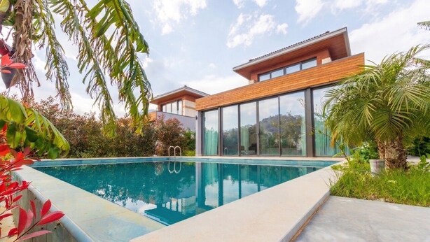 A modern house with a swimming pool, large windows, and a well-maintained garden.