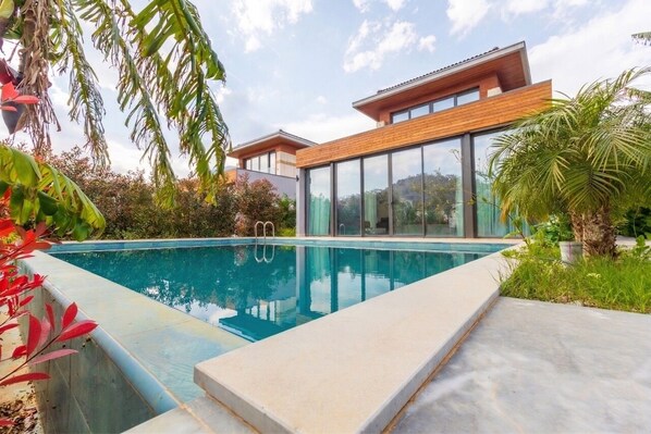 Una casa moderna con piscina, ventanas amplias y un jardín cuidado.