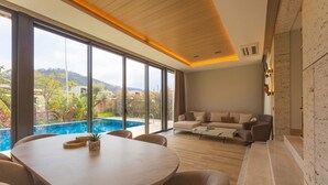 A modern living room with a pool view, a round dining table, and a sofa set.