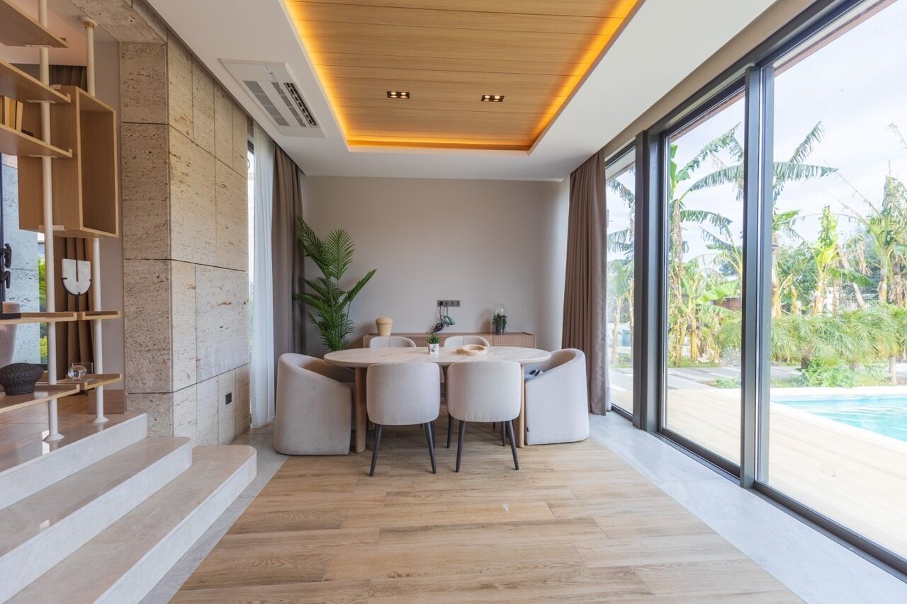 Un espace repas moderne avec une table ronde, des chaises et une vue sur une piscine.
