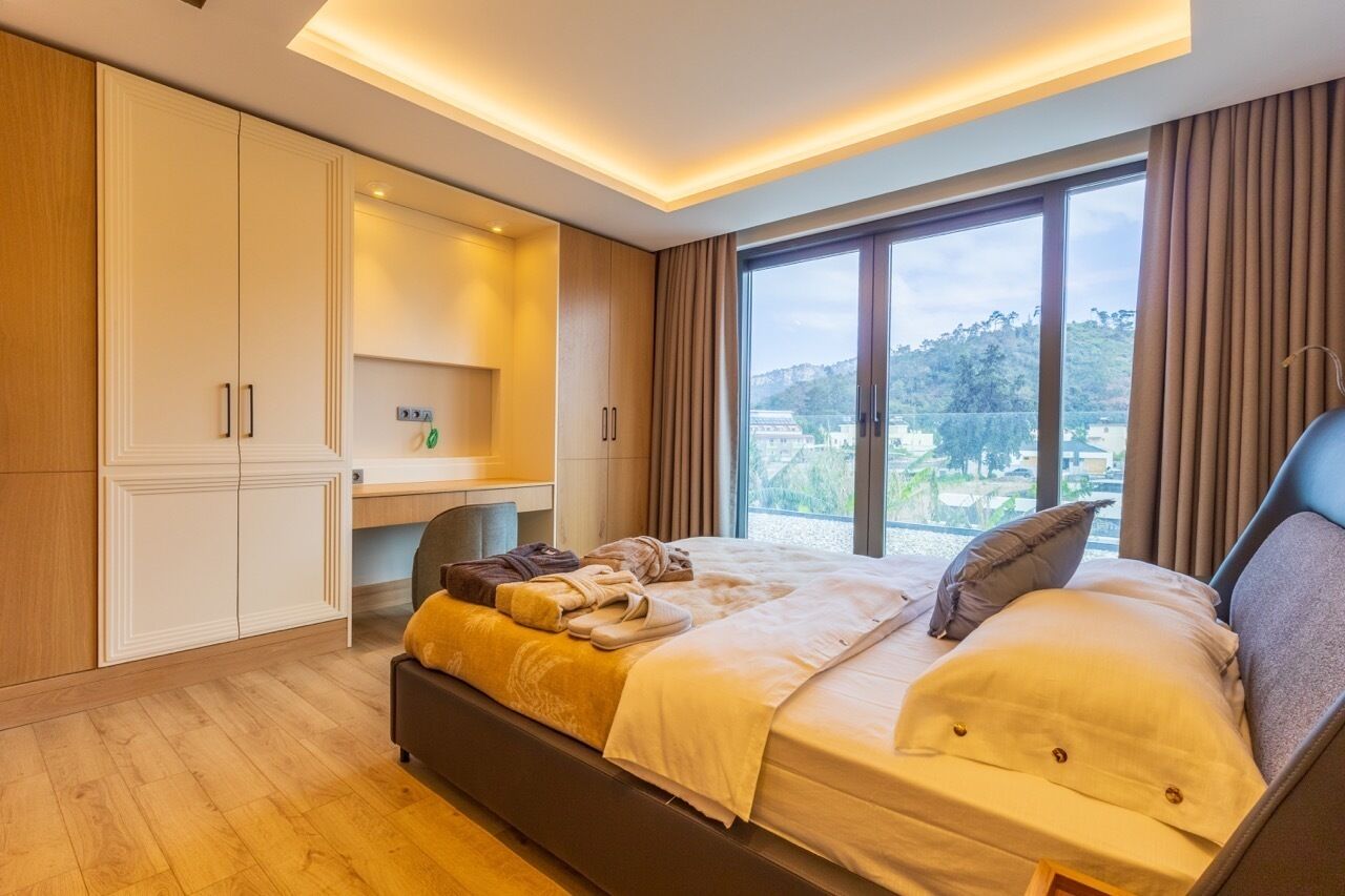 Quarto moderno com uma cama grande, uma escrivaninha e vista para o exterior.