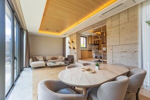 Una sala de estar moderna con una mesa de comedor redonda, un juego de sofá y una cocina con estanterías empotradas.